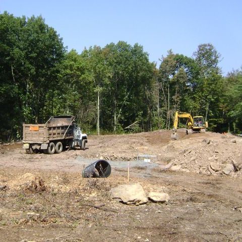 A dump truck is parked in the middle of a dirt field