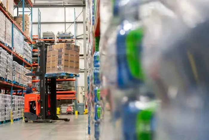 A forklift is moving a pallet of boxes in a warehouse.
