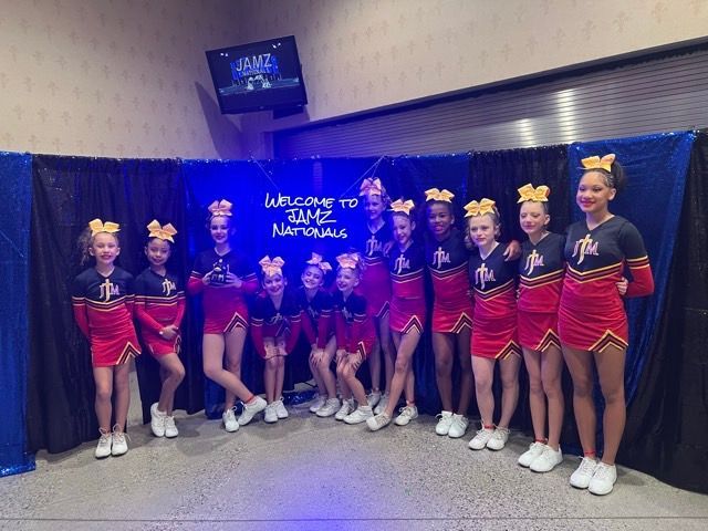 Cheer team posing in red-and-black uniforms at a national competition stage