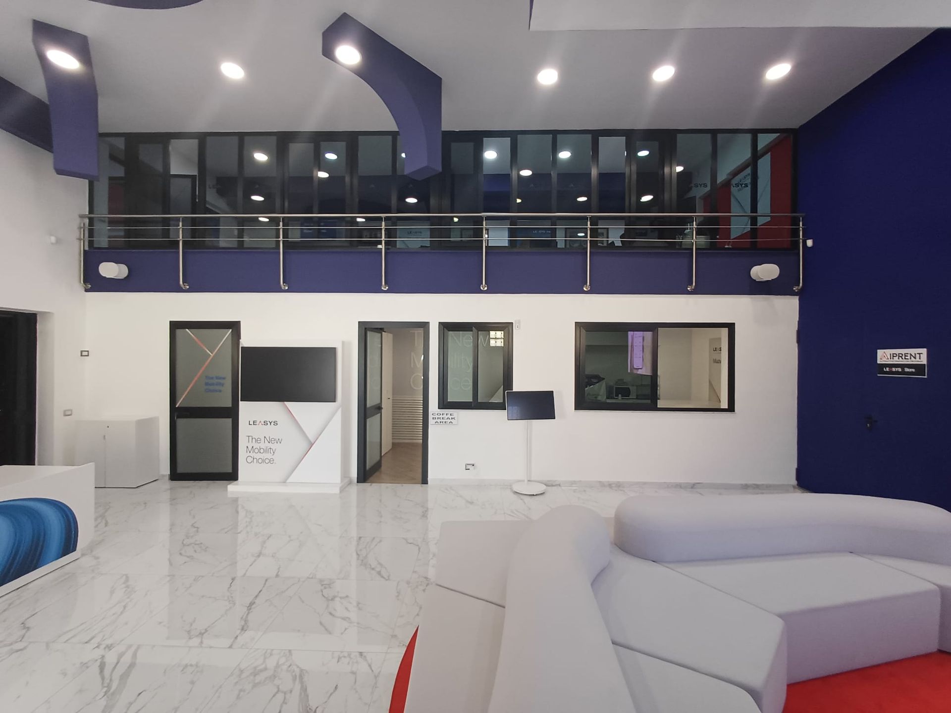 Salone interno moderno con pareti viola, finestre a soppalco e pavimenti in marmo bianco, visto dalla zona salotto.