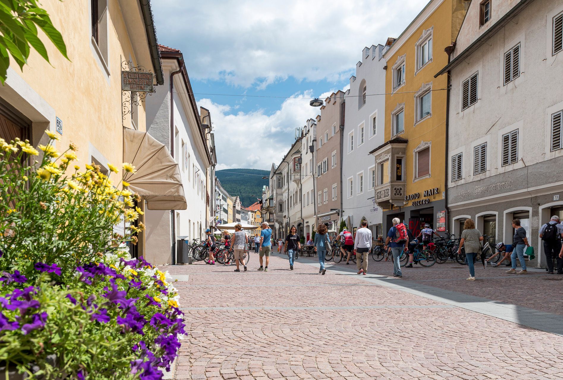 Eine Gruppe von Menschen geht eine Kopfsteinpflasterstraße in einer Stadt entlang.
