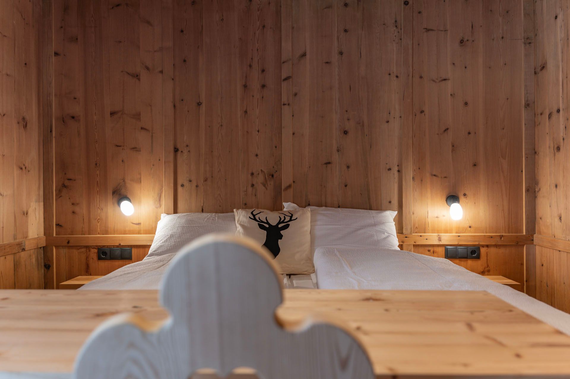 Ein Schlafzimmer mit einer Holzwand und einem Bett mit einem Hirschkissen darauf.