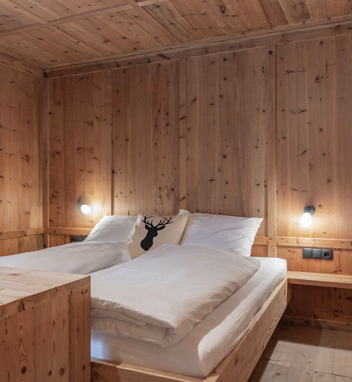 Ein Schlafzimmer mit Holzwänden und einem Bett mit weißen Laken