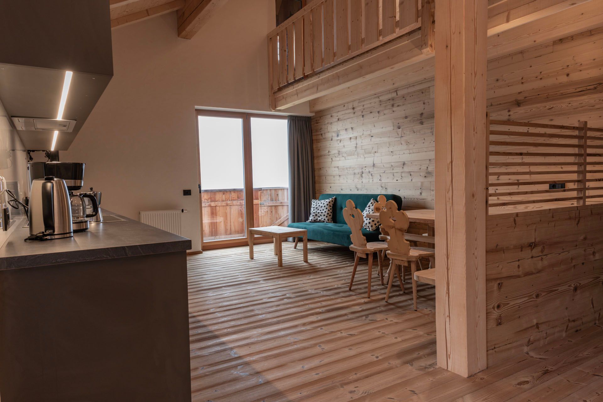 Ein Wohnzimmer mit einer blauen Couch, Stühlen, einem Tisch und einem Balkon.