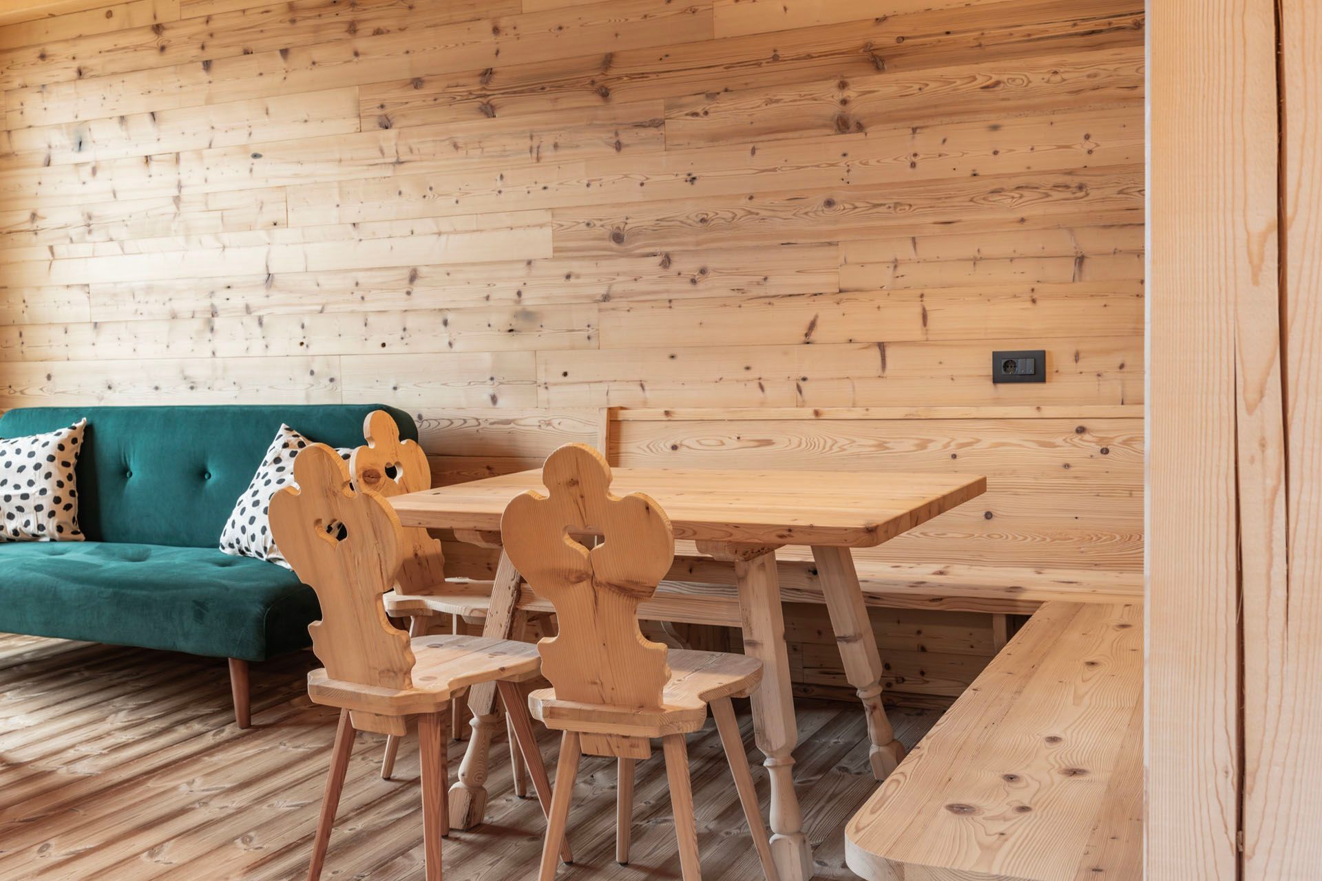 Ein Wohnzimmer mit einem Holztisch und Stühlen und einer grünen Couch.