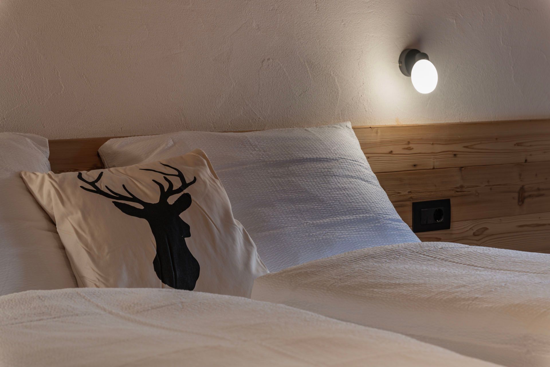 Ein Bett mit einem Hirschkissen darauf in einem Schlafzimmer.