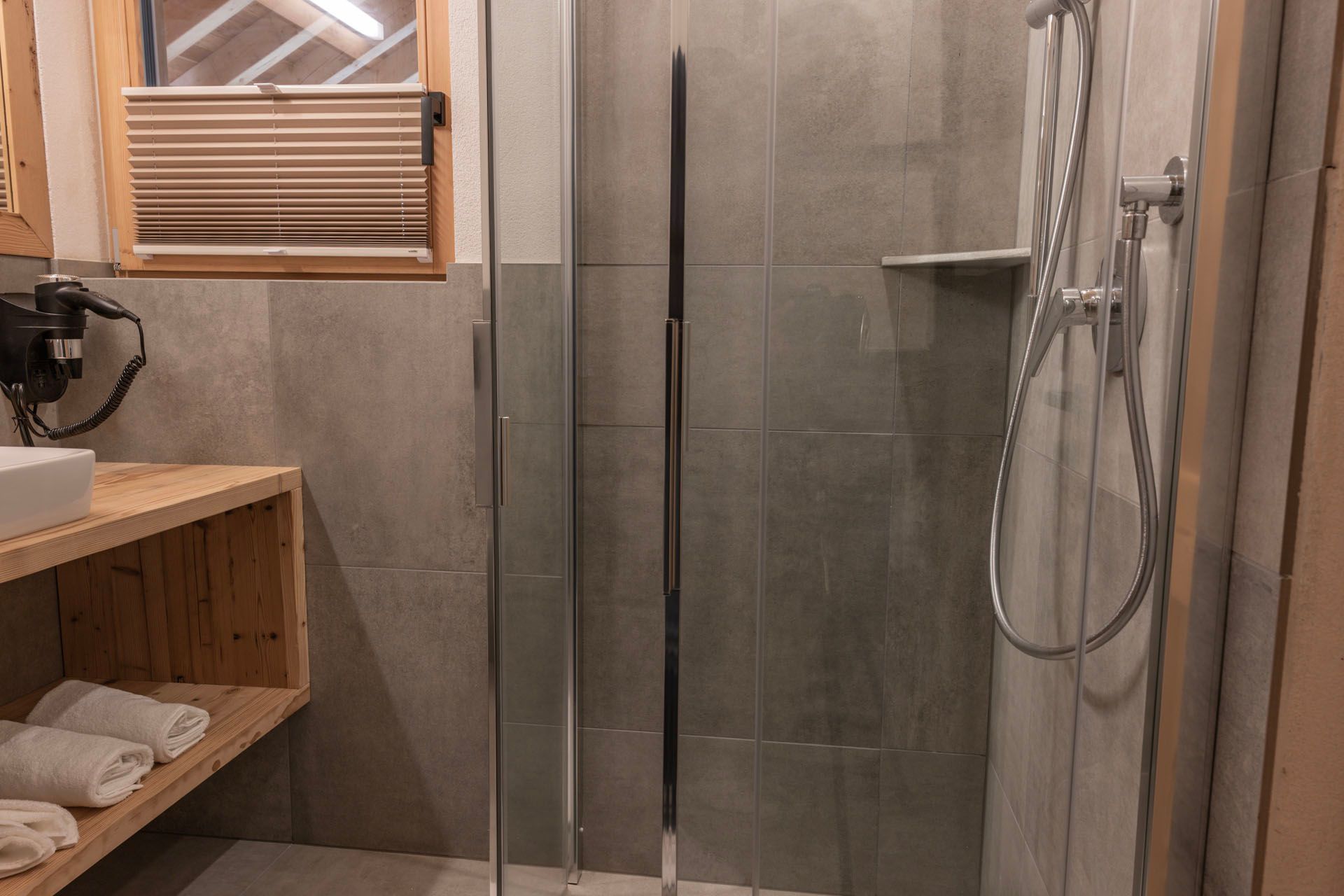 Ein Badezimmer mit ebenerdiger Dusche und Waschbecken.