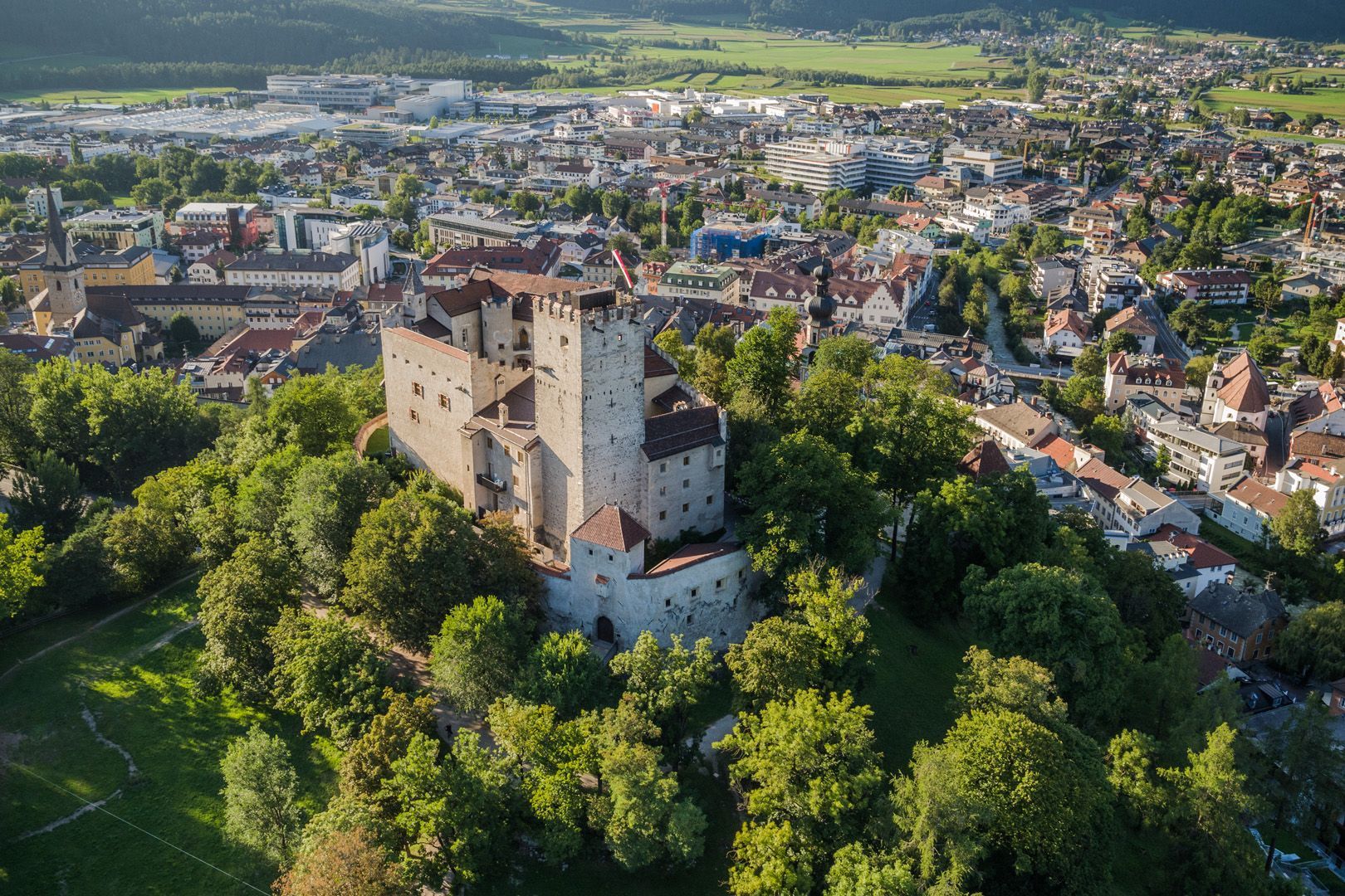 Eine Luftaufnahme einer Burg auf einem Hügel mit einer Stadt im Hintergrund.