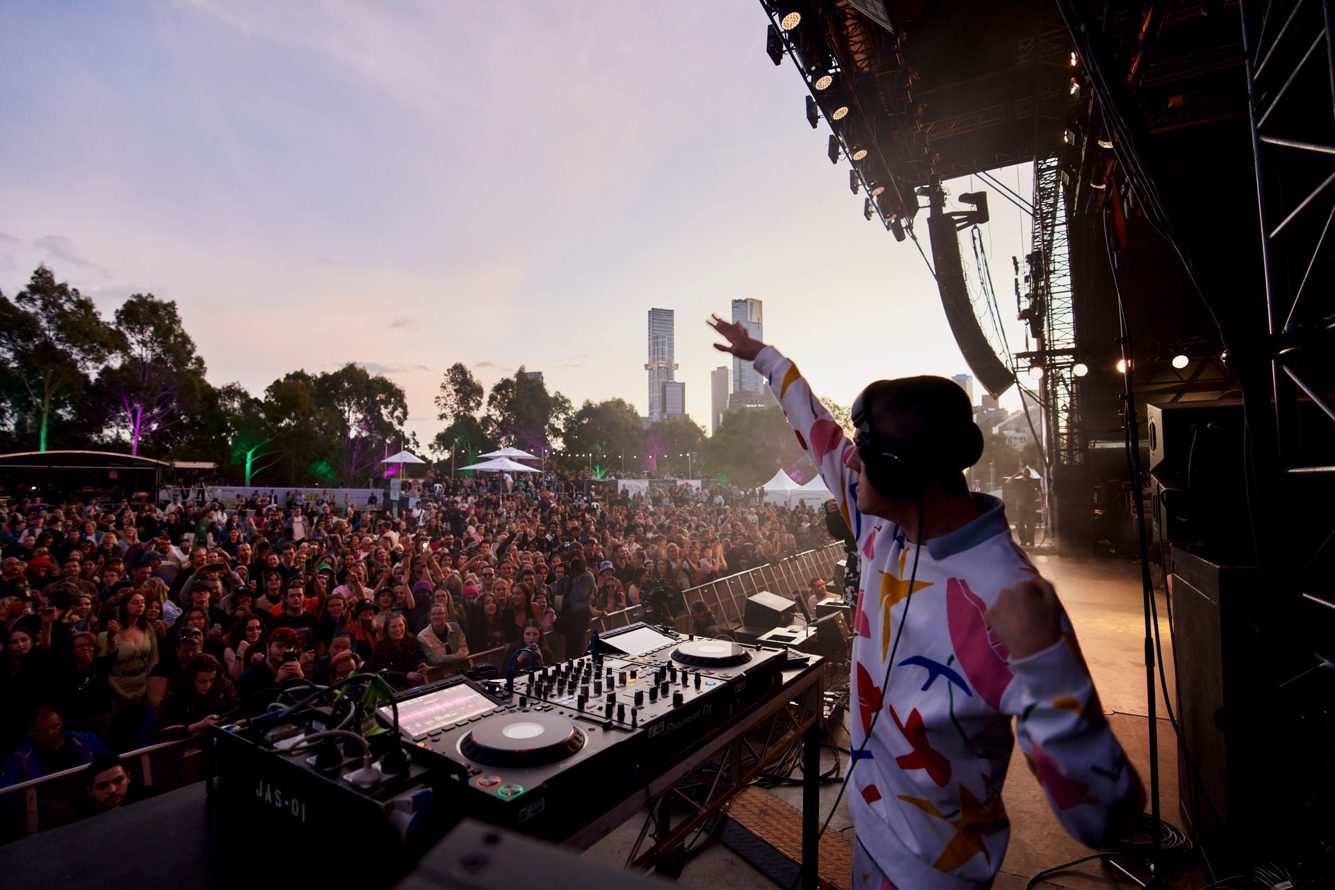 Recipient Cooper DJ's to the Ability Fest crowd on main stage, he has one arm raised.