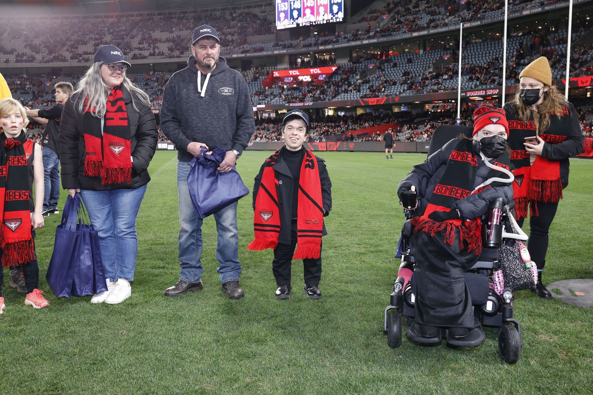 DAF recipients and families wearing Essendon scarfs on Marvel oval in a guard of honour.