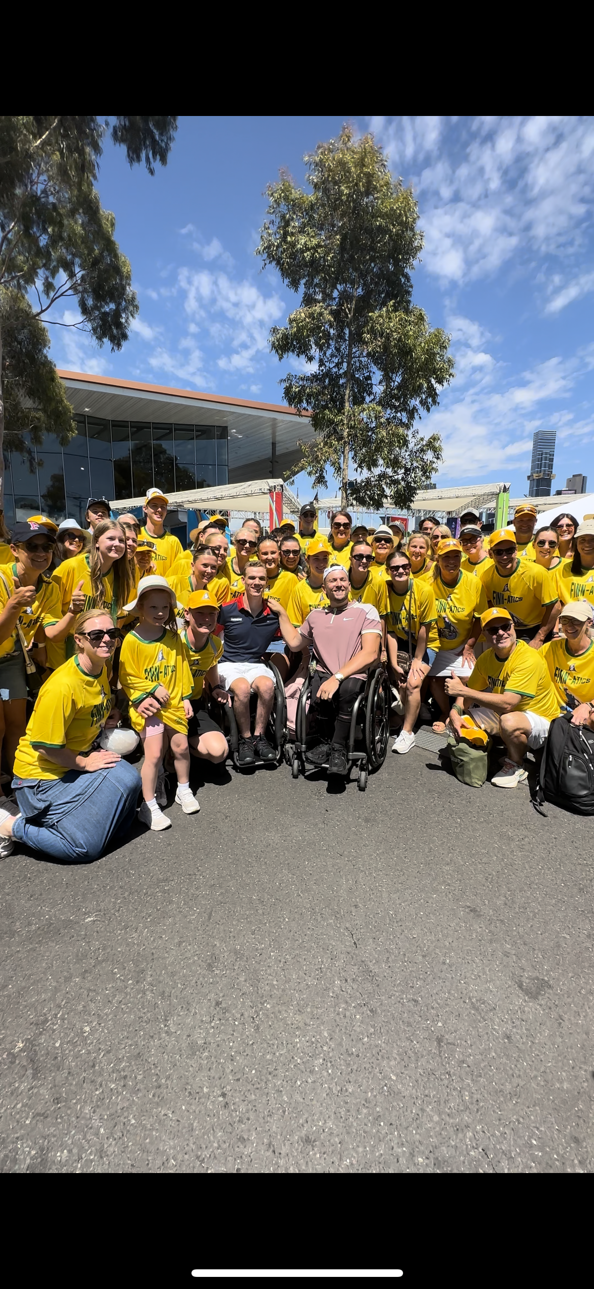 Group shot of Dylan (middle) and wheelchair tennis player Finn Broadbent (middle) surrounded by his fans dressed in yellow. 