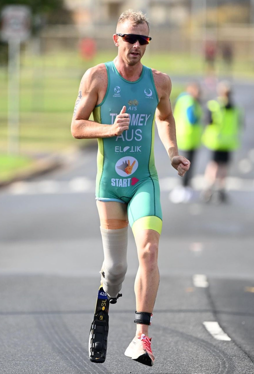 Recipient Liam wearing Aussie Lycra kit, competing in the leg run of a triathlon. Liam wears a prosthetic on the left leg.