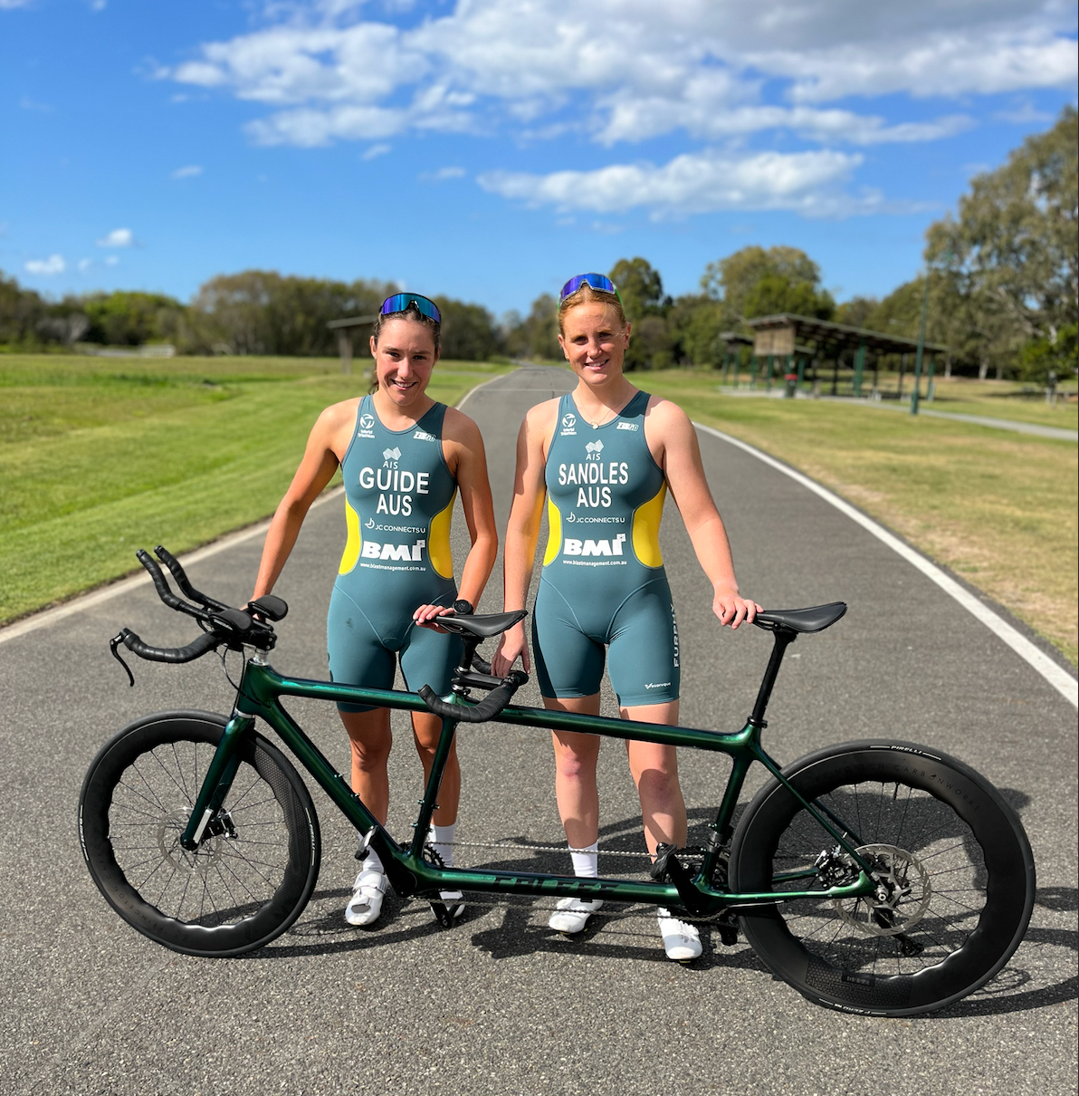 Recipient Maggie (right) and guide (left) pose for photo in Australian uniforms in front of a tandem bike.