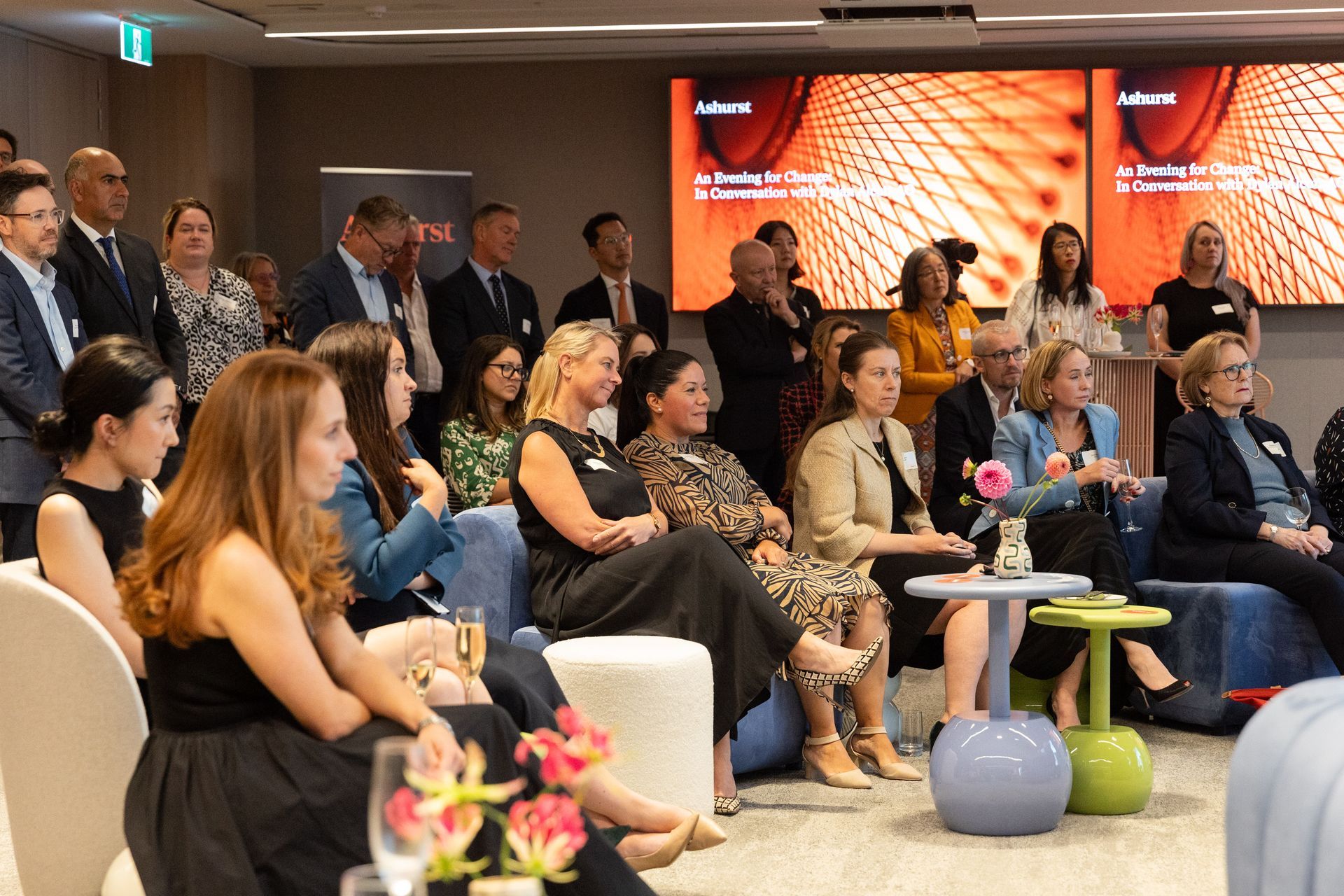 Crowd watching and listening to panellists inside a large board room.