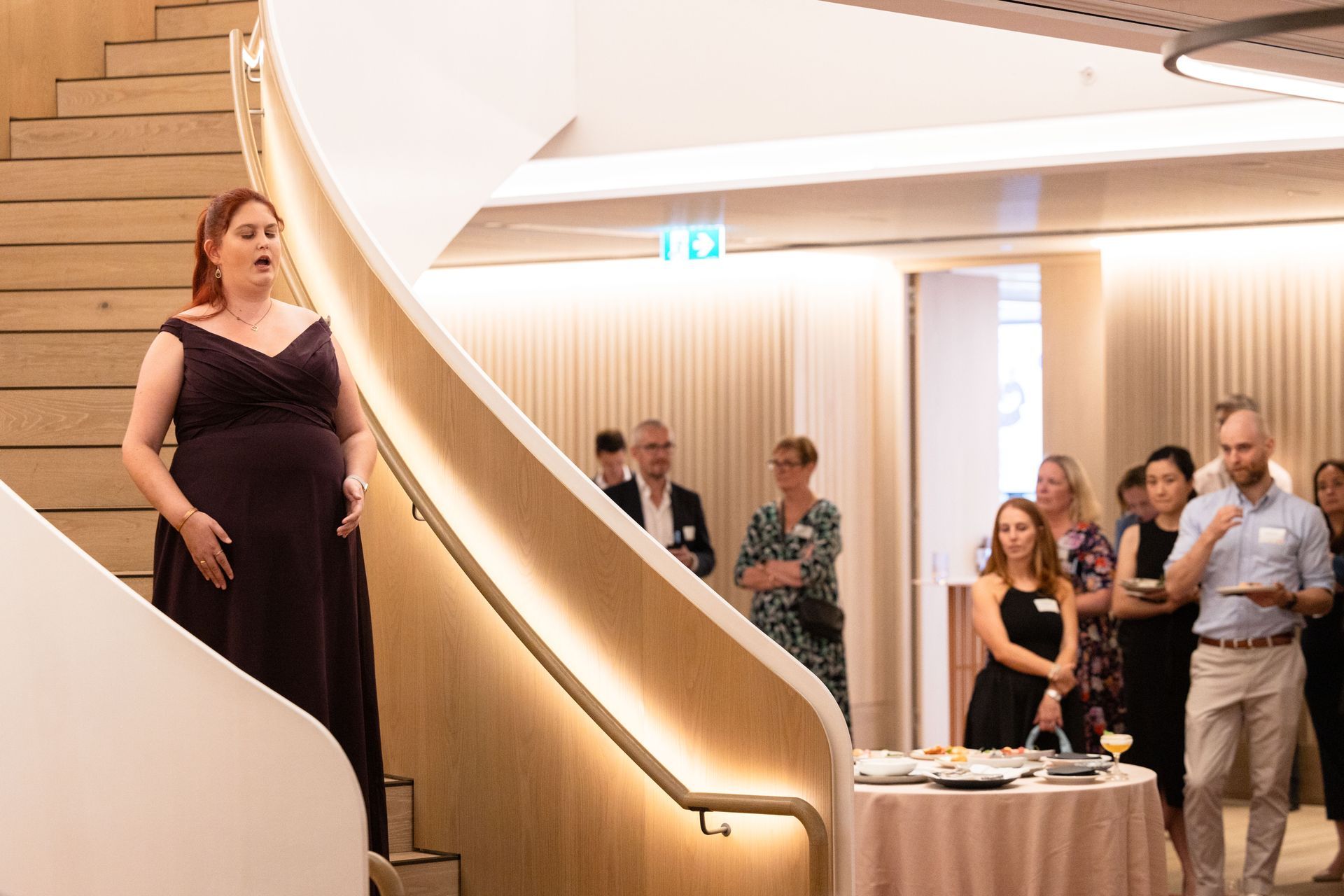 Recipient Kirsten singing on a winding staircase to a crowd.