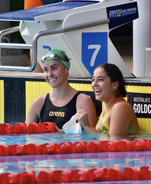 Recipient Hannah (left) in the pool post race with swimming cap, next to fellow competitor in the next lane (right).
