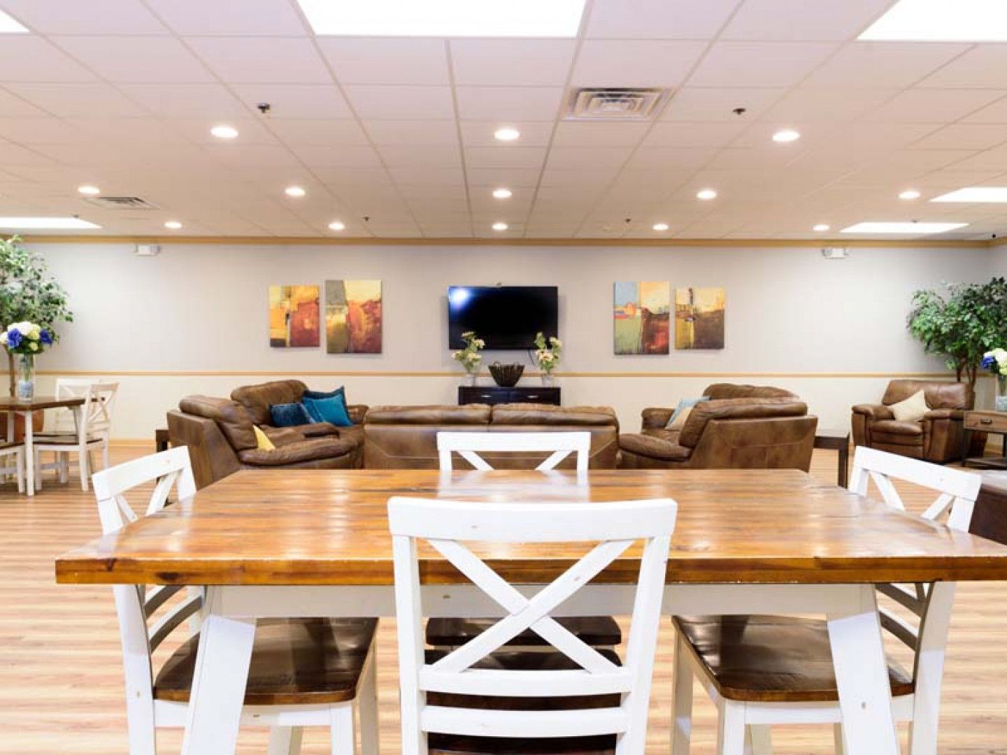 Modern lobby lounge with wooden tables, brown sofas, wall art, and a TV on the back wall