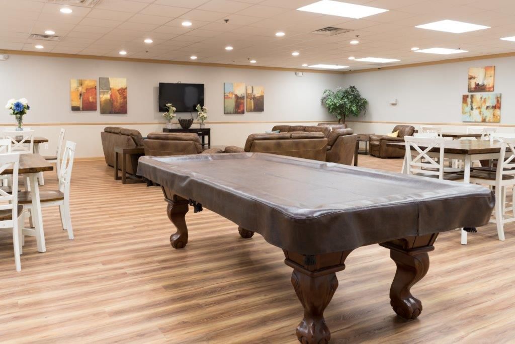 Recreation room with pool table, couches, white chairs, wall art, and a TV on the far wall