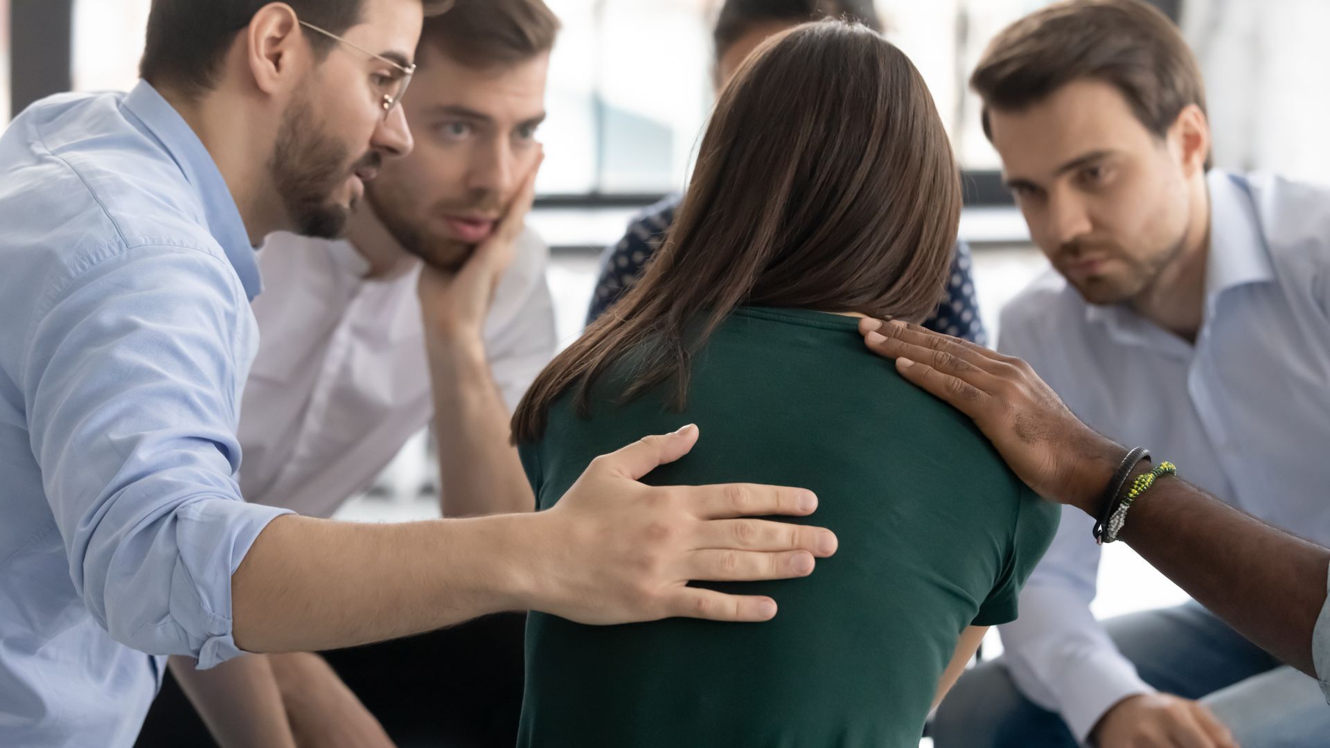 Coworkers lean in to comfort a distressed person in a meeting room