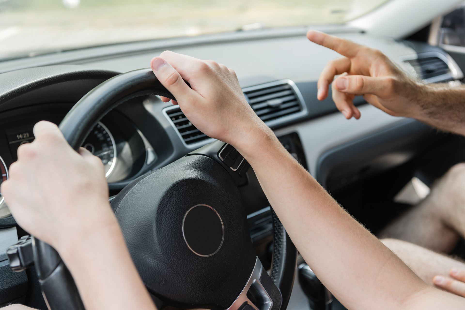 Hands on steering wheel and dashboard inside a car during driving lesson