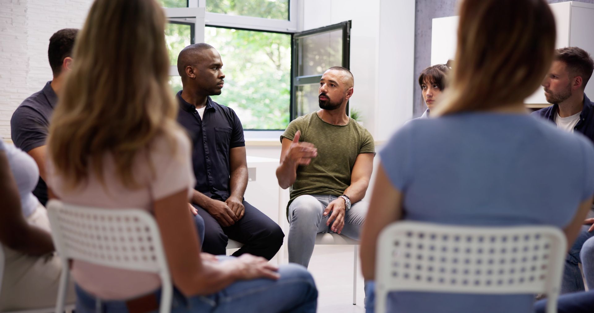 People in a circle, hands clasped, at a support group session.