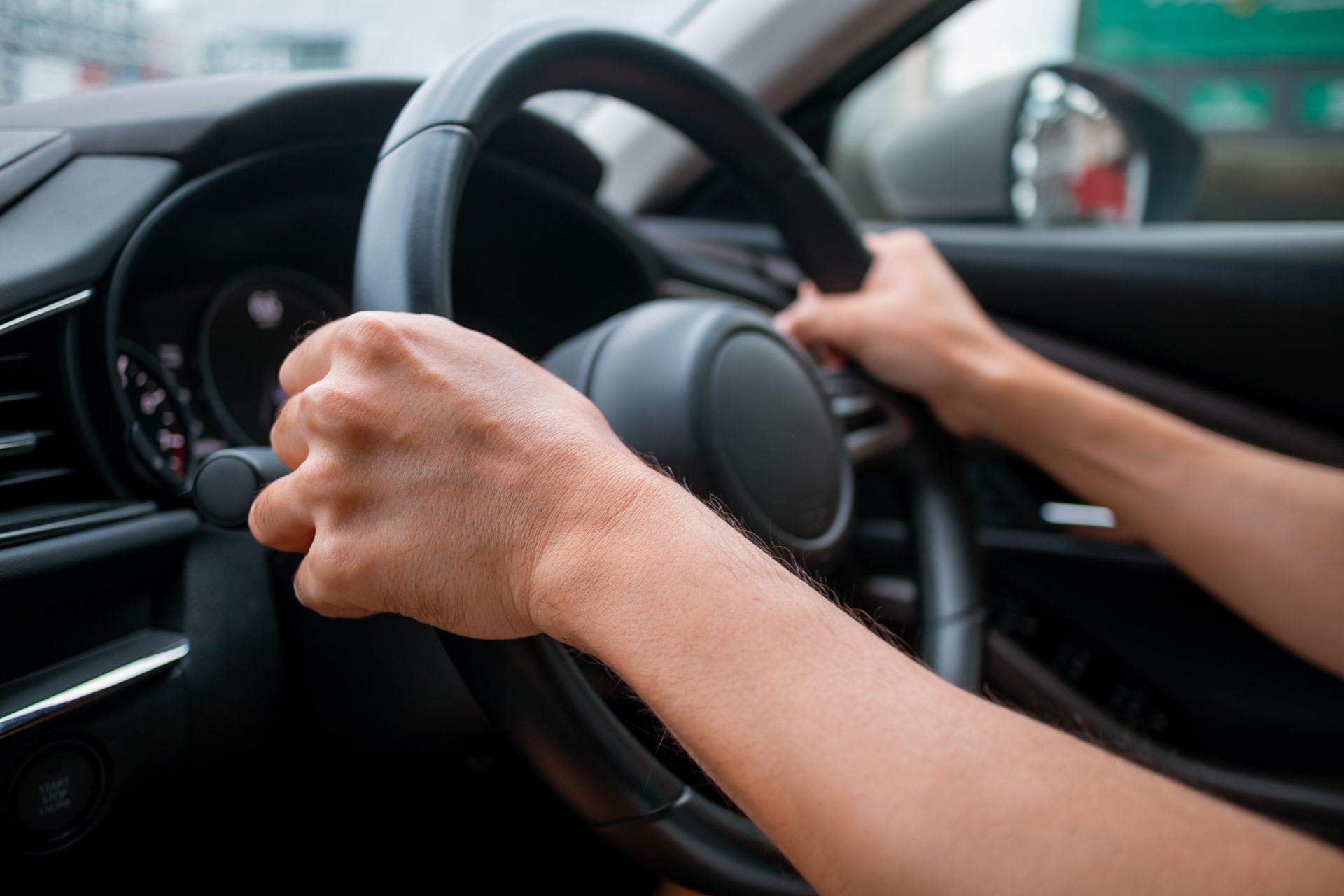 Hands gripping a car steering wheel while driving inside a vehicle