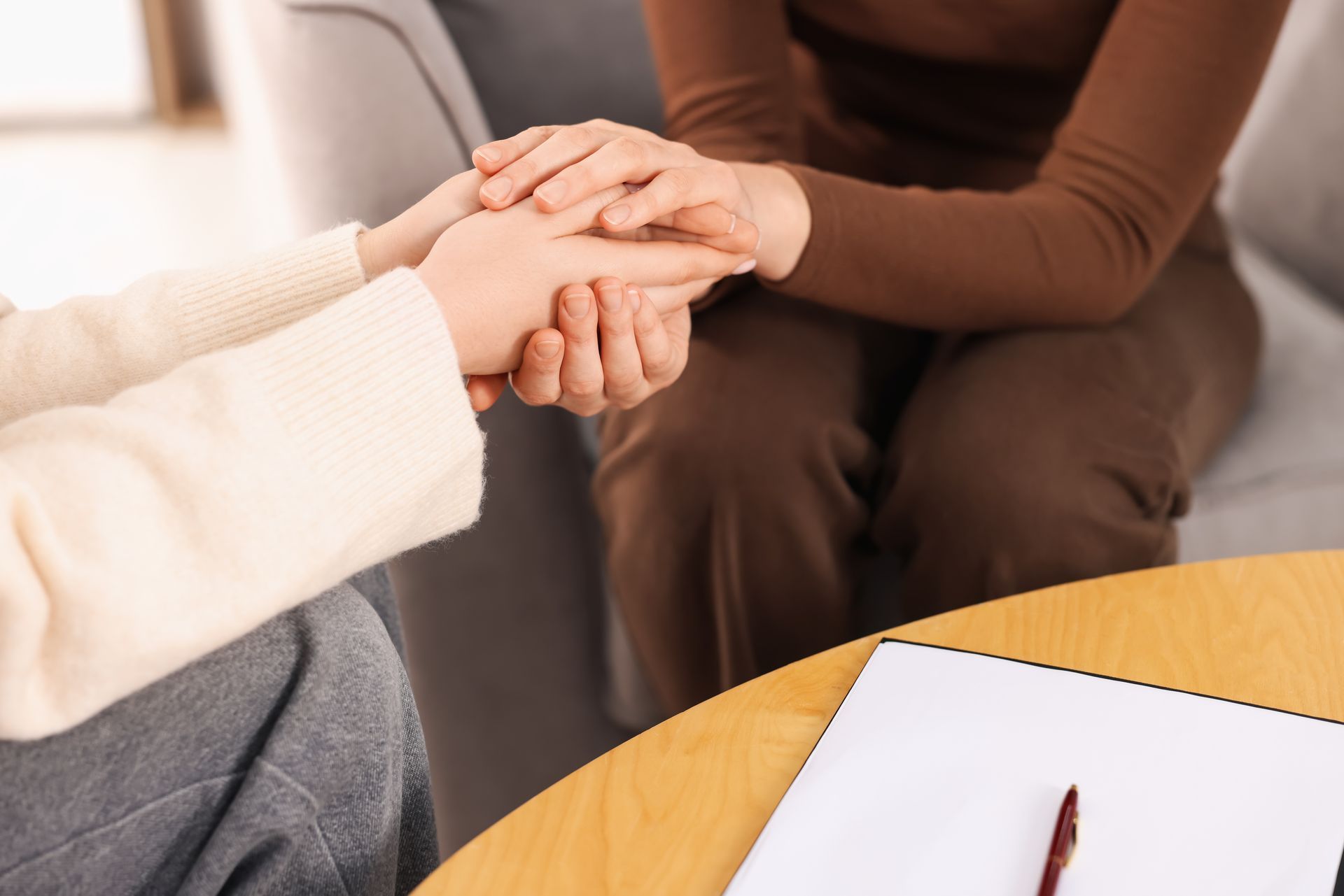 People in a circle, hands clasped, at a support group session.
