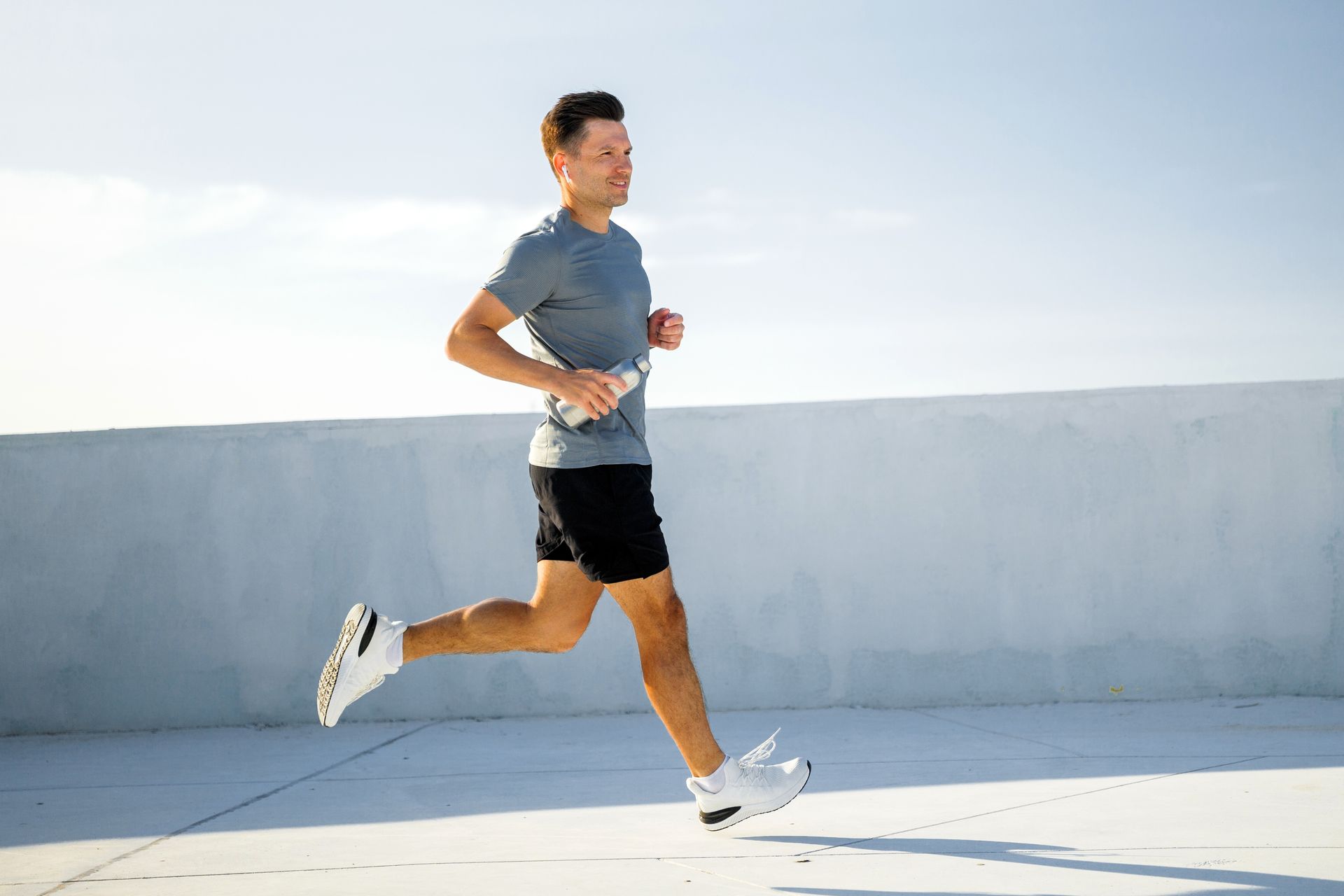 Man running on a bright rooftop in athletic clothes under a clear sky
