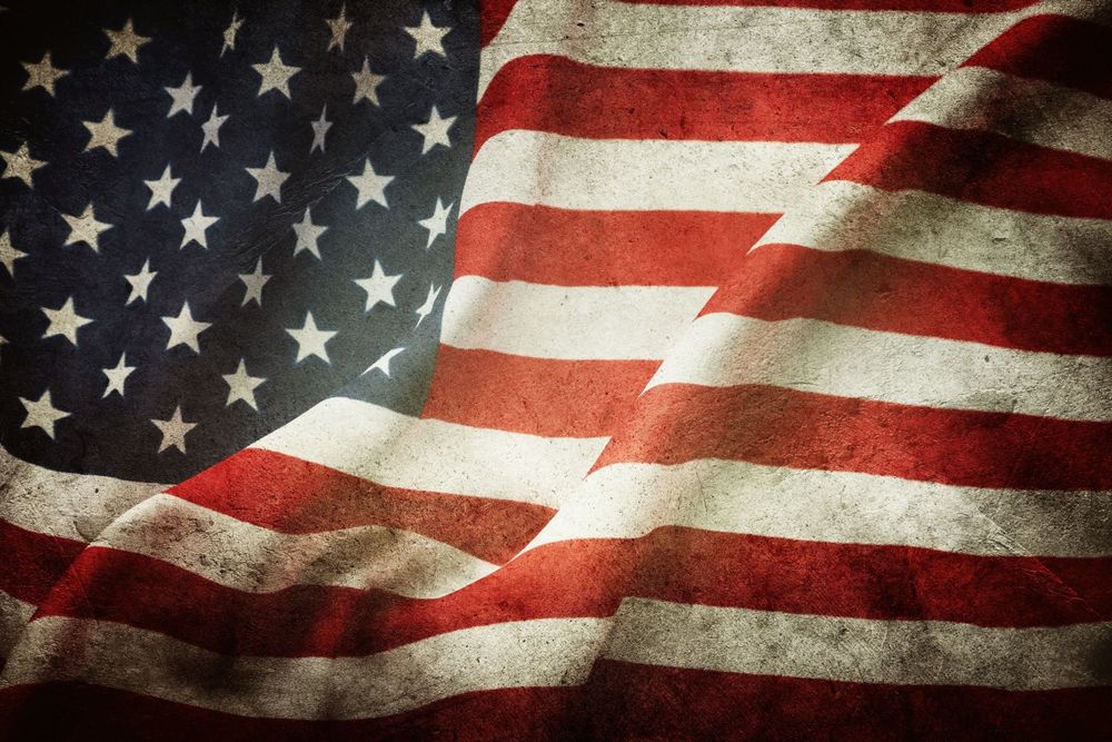 A distressed, weathered American flag with visible folds and a vintage, textured appearance.