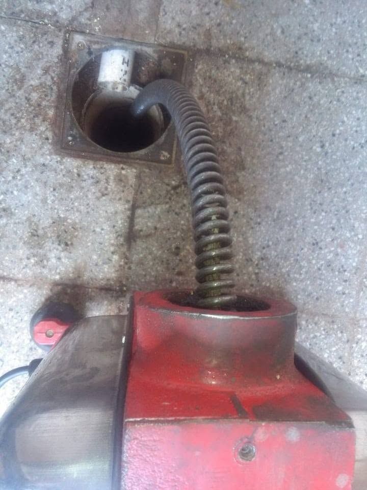 Manguera flexible conectada a una máquina roja y a una abertura de ventilación en el suelo