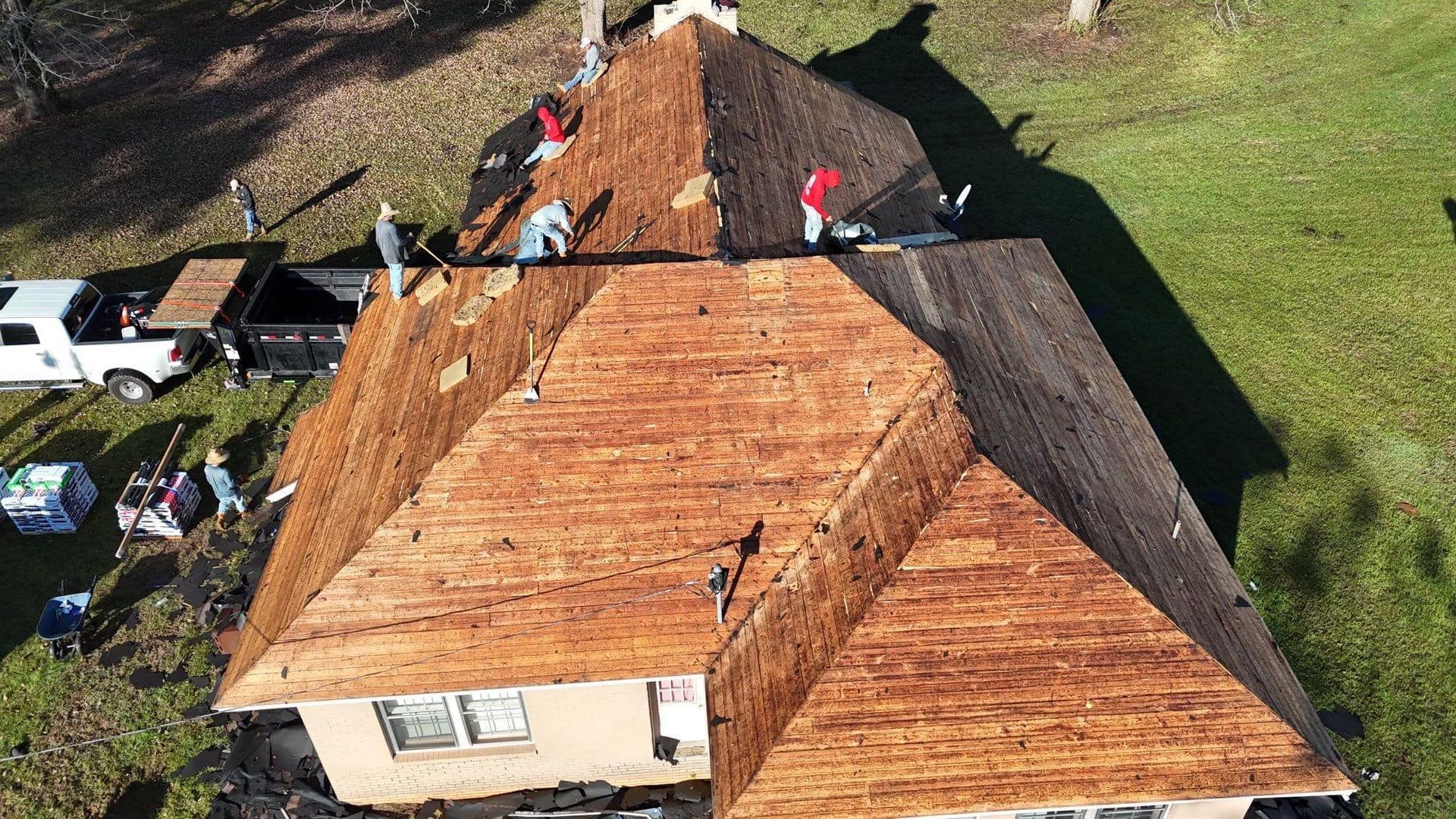 An aerial view of a house with a wooden roof being installed.