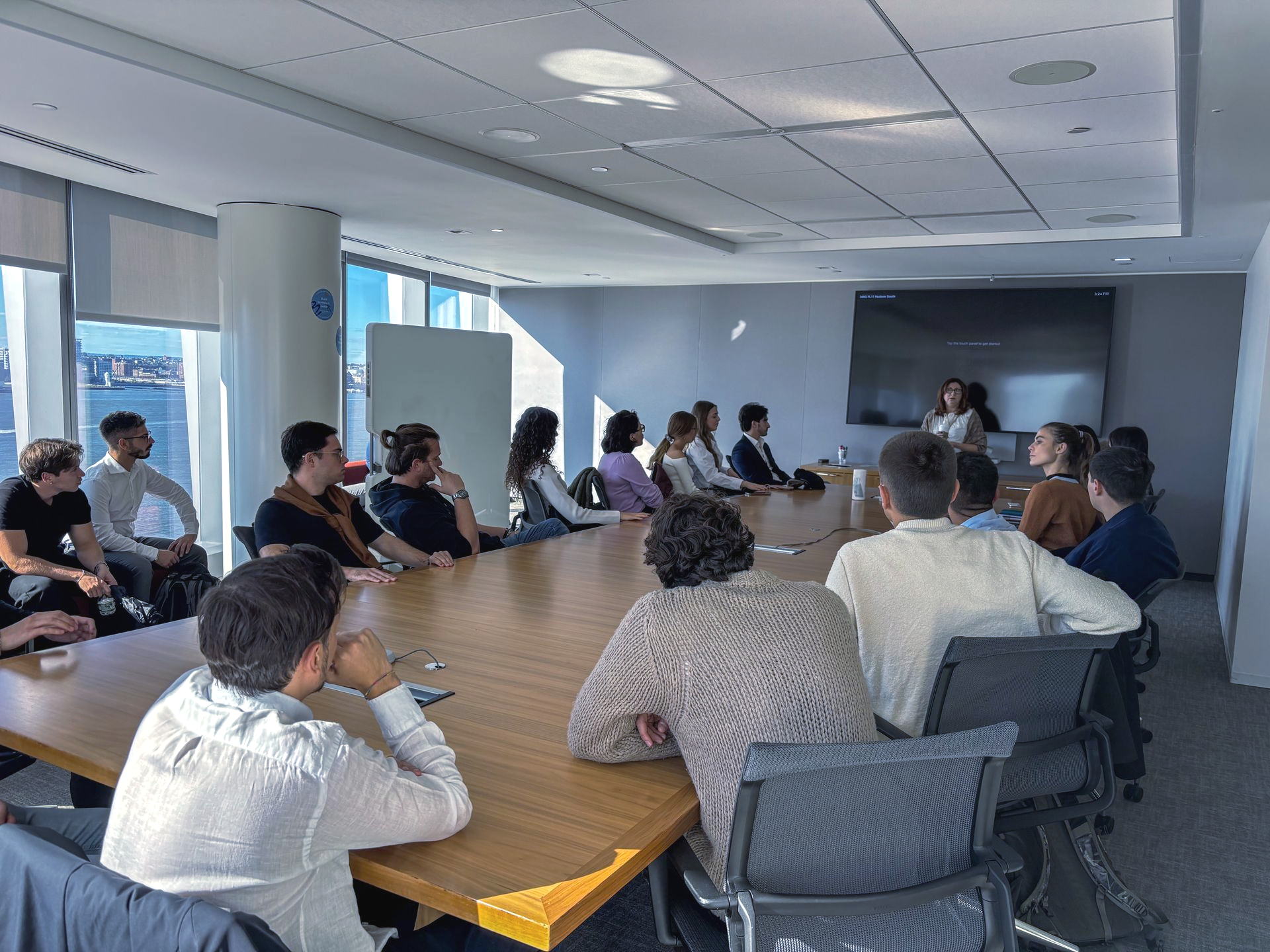 People seated around a large conference table in a bright meeting room.