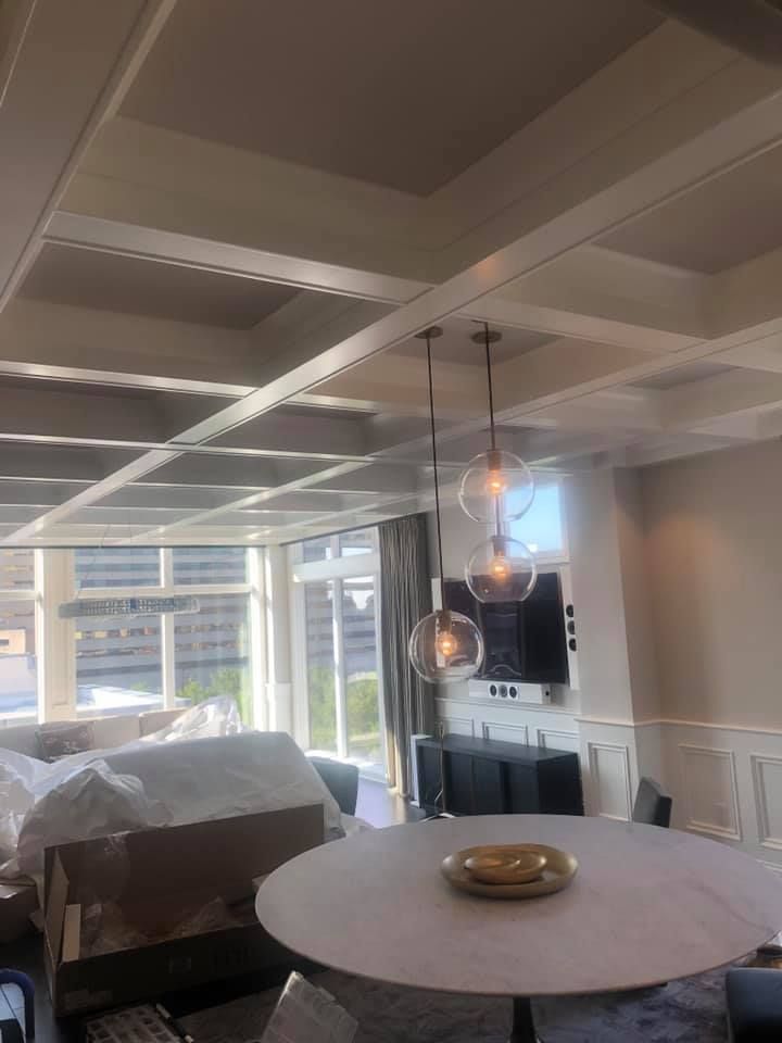 Dining room with a white coffered ceiling, round table, and three globe pendant lights.