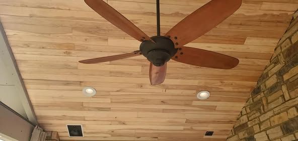 Wooden ceiling with a ceiling fan and recessed lighting. Brick wall on the right.