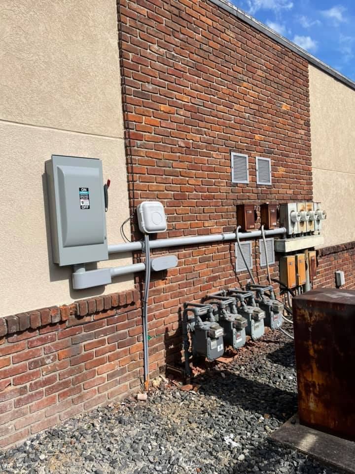 Electrical and gas meters on brick building exterior. Gray box, pipes, and meters.