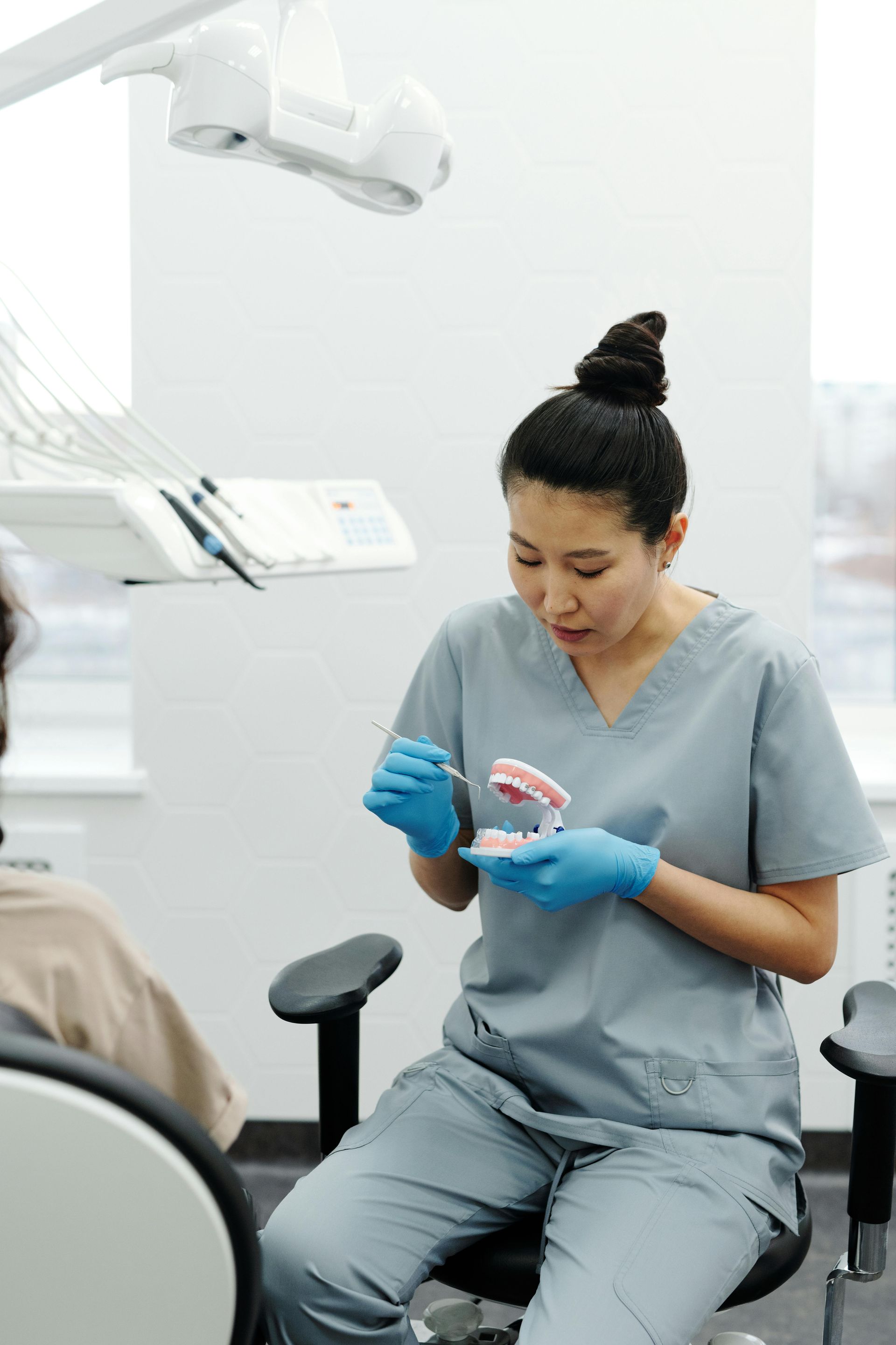 GILROY DENTAL SMILES_Dentist in mask and glasses examining patient's teeth in a dental office.