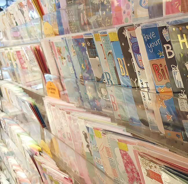 Greeting cards displayed in a bright shop rack, with colorful designs and floral patterns