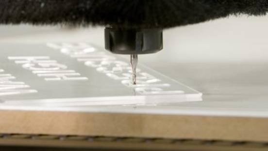 Close-up of a CNC machine engraving a white surface with a spinning cutting tool