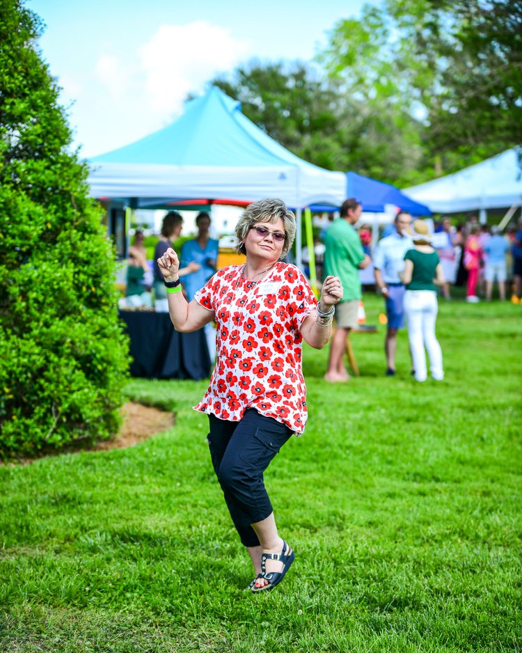 A woman is dancing in the grass at a festival.