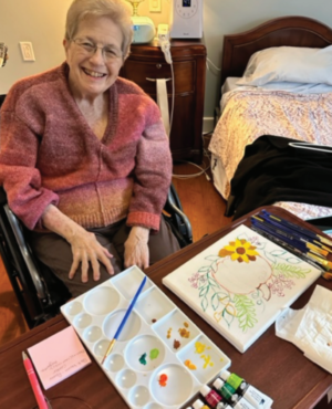 A woman is sitting at a table with a painting on it