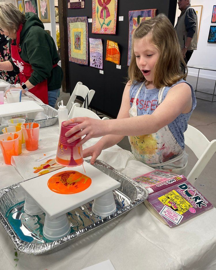 A little girl is painting on a canvas with a cup