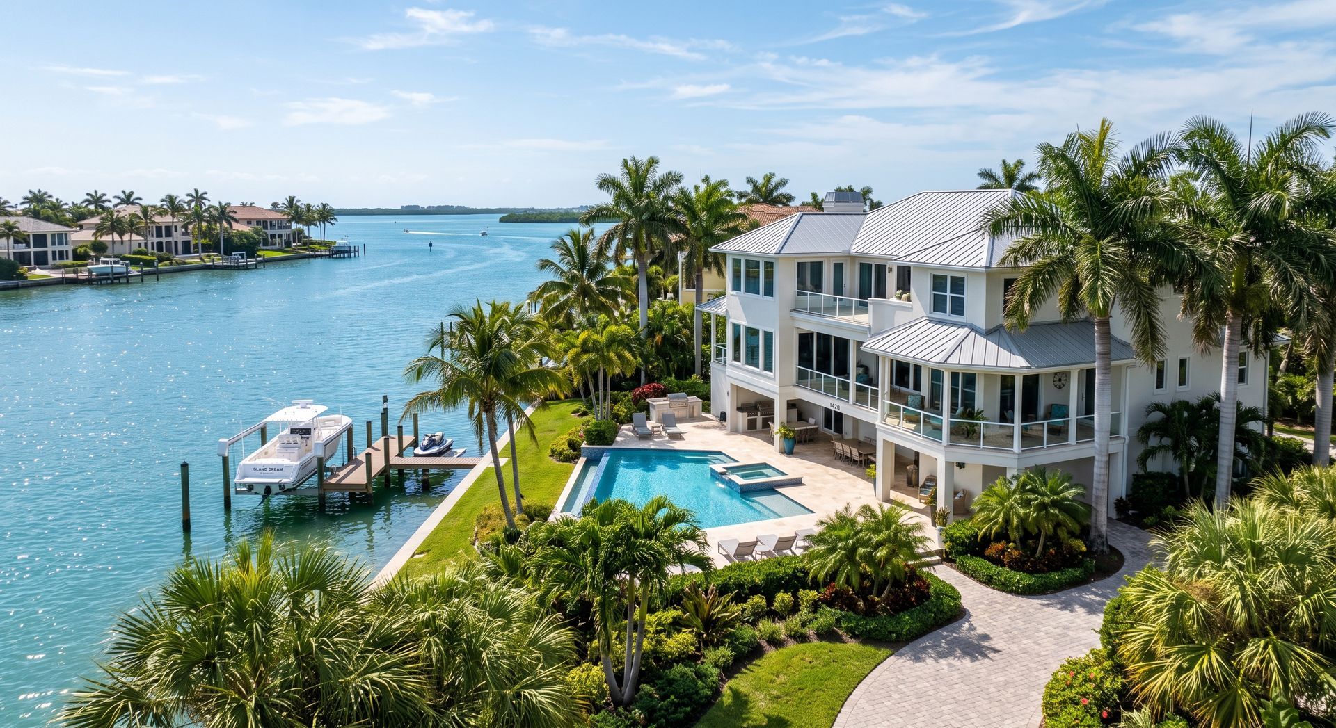 Waterfront luxury home with pool, palm trees, and dock beside a bright blue canal