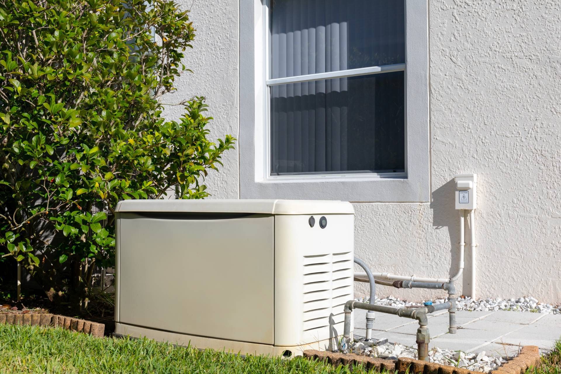 A home backup generator outside of a residential house in a well-maintained yard