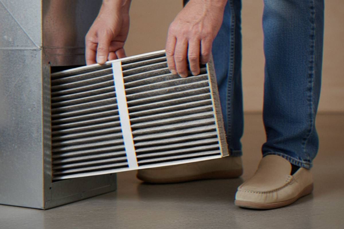 A homeowner changing out their dirty HVAC unit's air filter as a preventative maintenance task