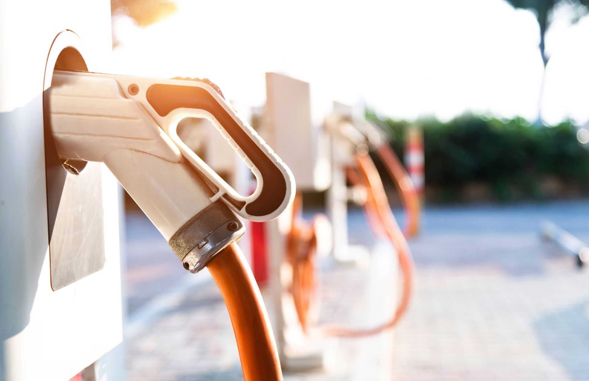 Close-up image of a commercial electric vehicle charging station with three orange and white chargers near Somerset, KY