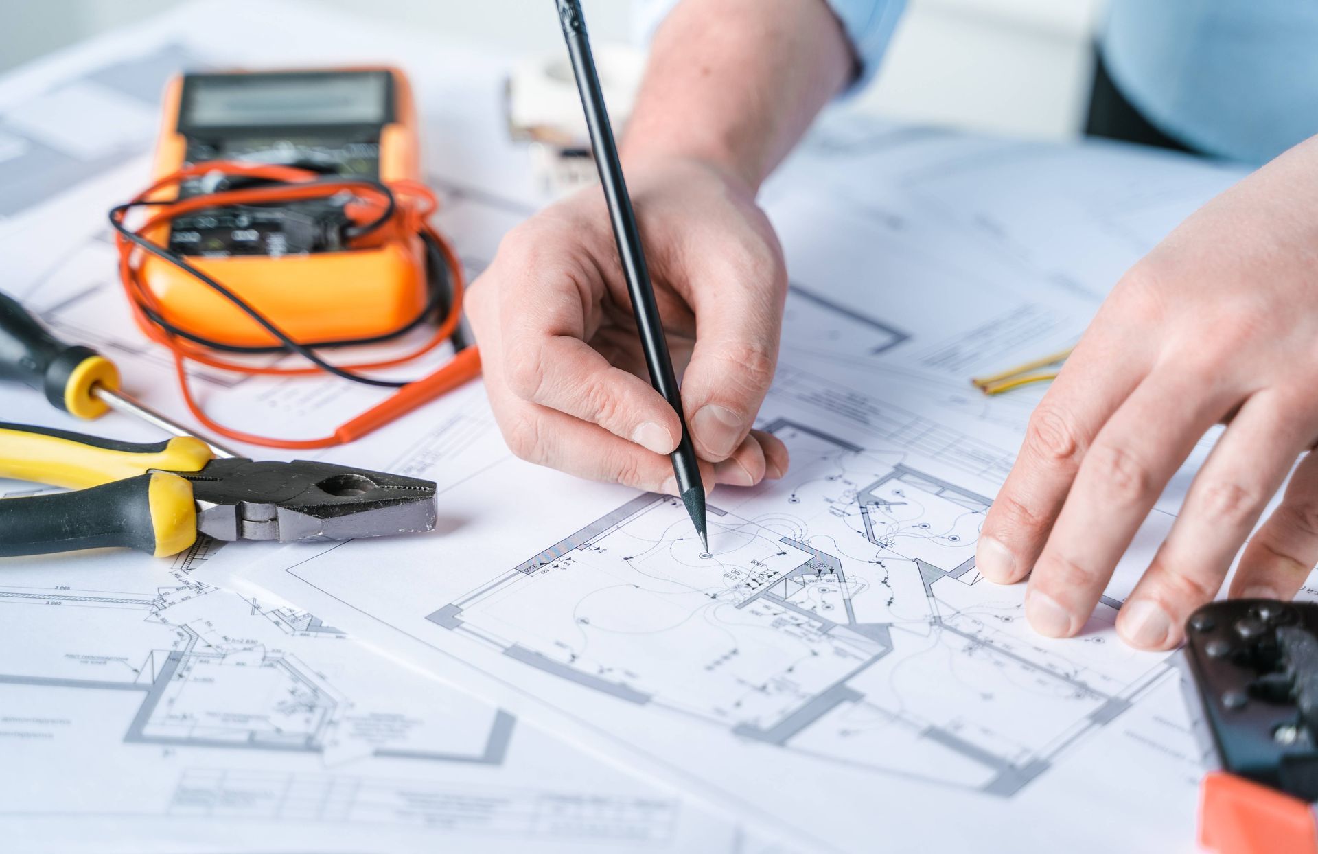 Up-close image of a professional electrician's hand drawing blueprints for an electric project near Somerset, KY