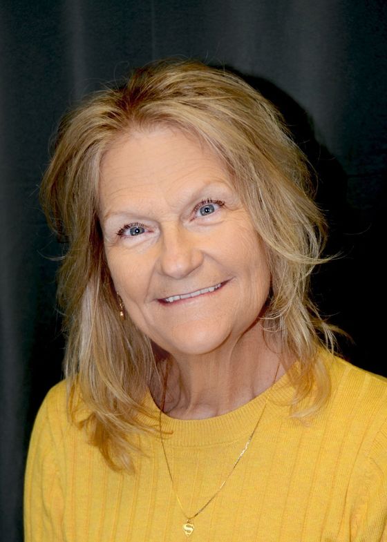 Smiling woman in a yellow top against a dark background