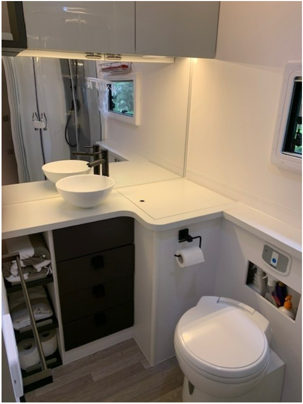 A bathroom with a toilet , sink and mirror.