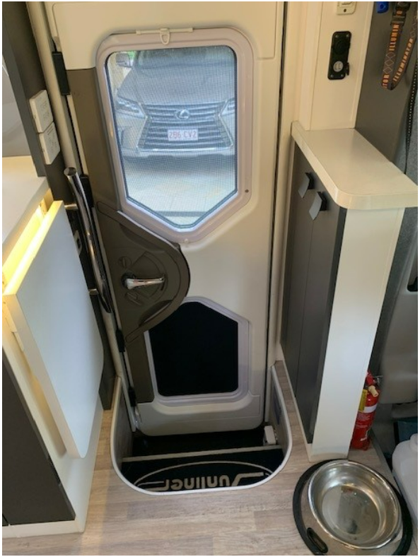 A rv with a dog door and a bowl of food