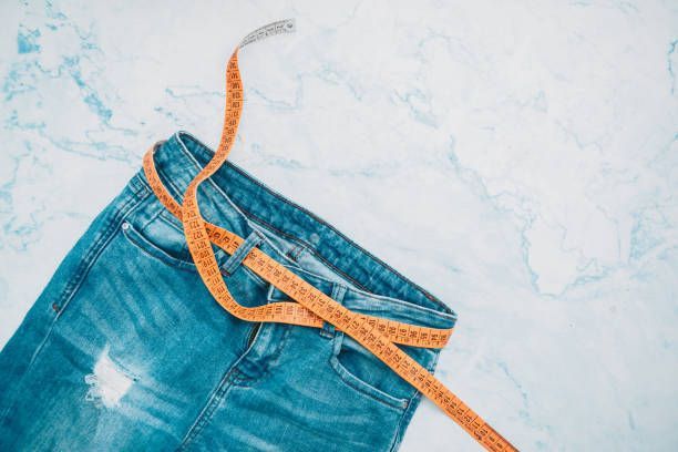 A pair of jeans with a measuring tape around it.